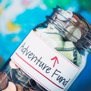 American money jar with Adventure Fund label and defocused globe
