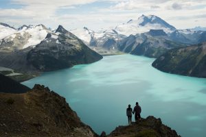 Couple embracing at a stunning vantage point overlooking a glacial lake in British Columbia, Canada's Coast Mountain Range.
